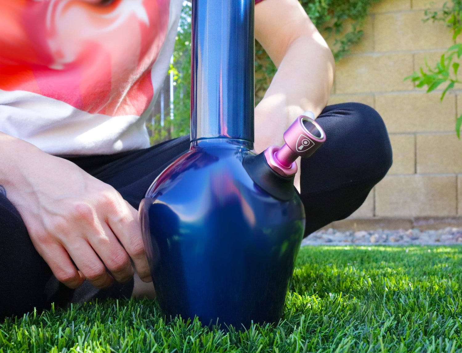 Person sitting on grass with Blue Chill Steel bong and Invincibowl bong bowl and downstem.